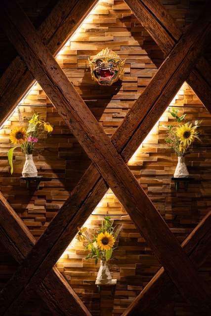 Détail mural en bois géométrique avec tournesols en vase, décoration intérieure Restaurant l'Orchidée