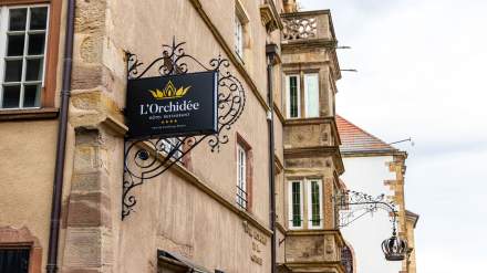 Enseigne en fer forgé "L'Orchidée Hôtel Restaurant 4 étoiles" fixée sur la façade en grès, Ensisheim Haut-Rhin