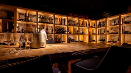 Bar au comptoir en bois avec étagères rétroéclairées garnies de bouteilles, Restaurant l'Orchidée